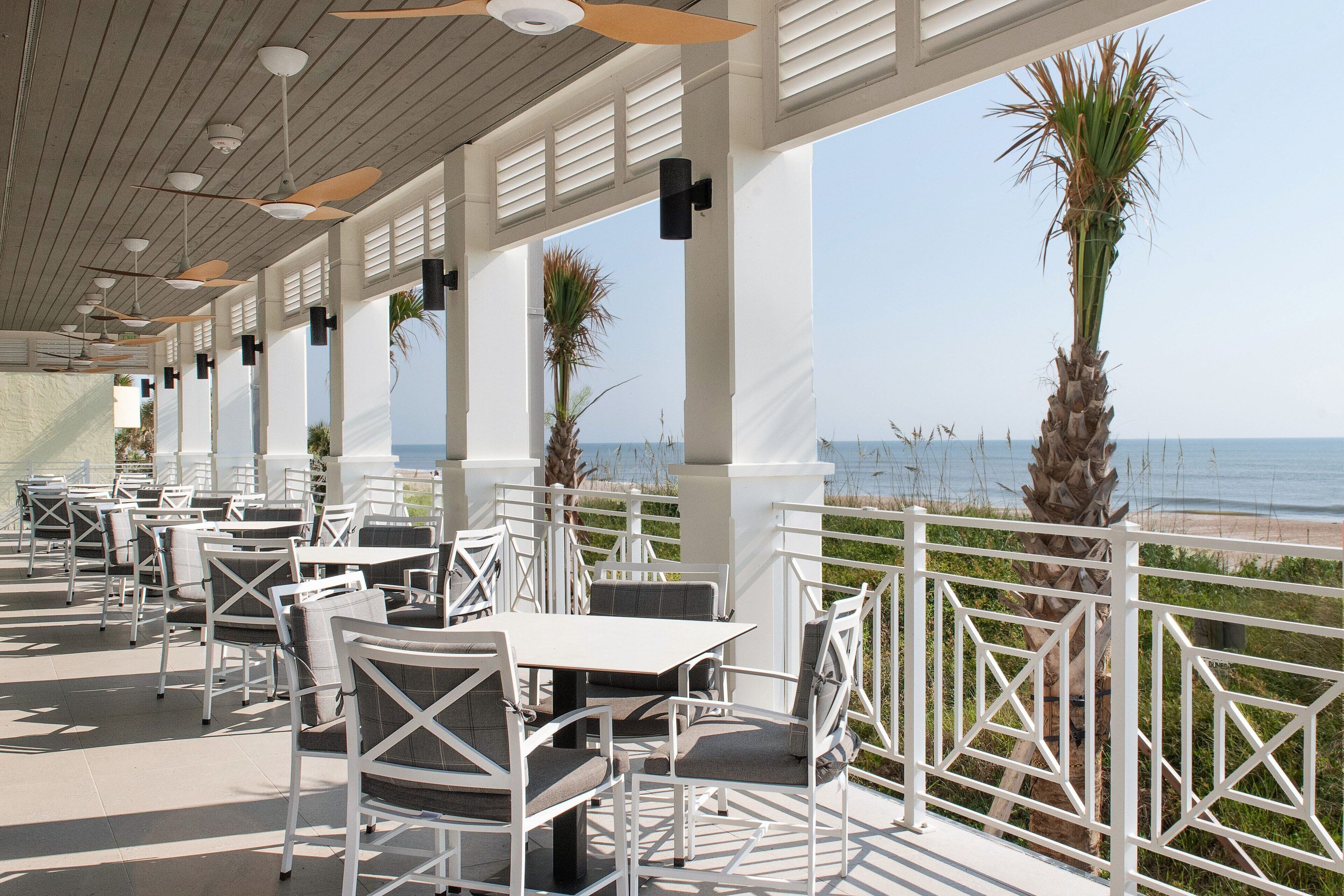 An outdoor patio with white furniture and a view of the ocean.
