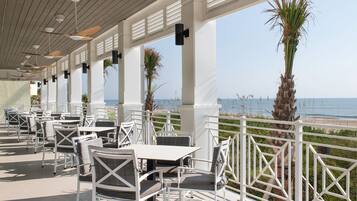 An outdoor patio with white furniture and a view of the ocean.