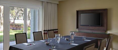 A conference room with a large table, chairs, a television, and a view of the outdoors.