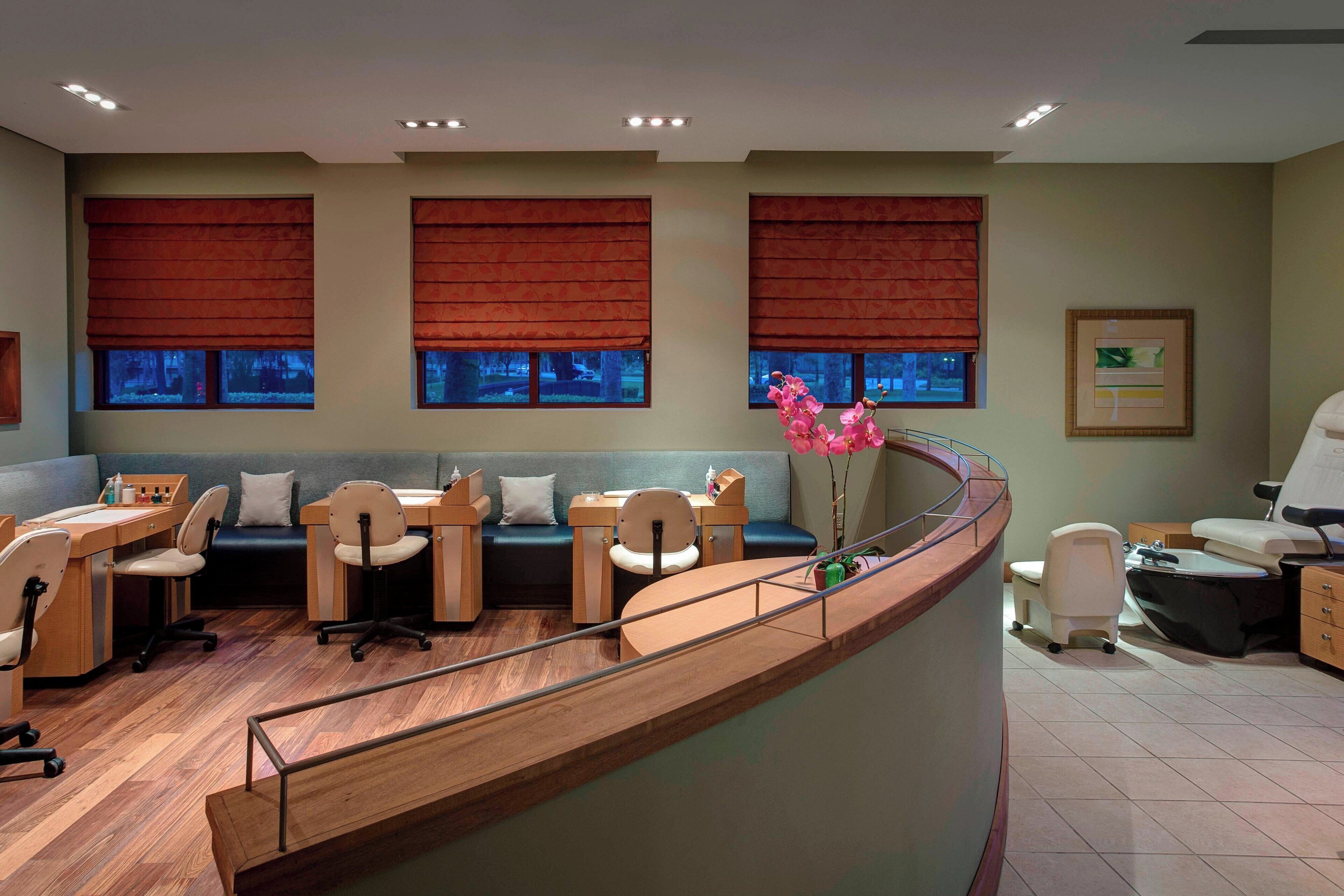 A reception area with a curved desk, several chairs, a sofa, and a small table with a vase of flowers.