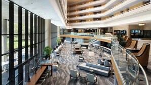 A multi-level hotel lobby with a central seating area, glass railings, and a view of the outdoors. - Sawgrass Marriott Golf Resort & Spa (Ponte Vedra Beach)