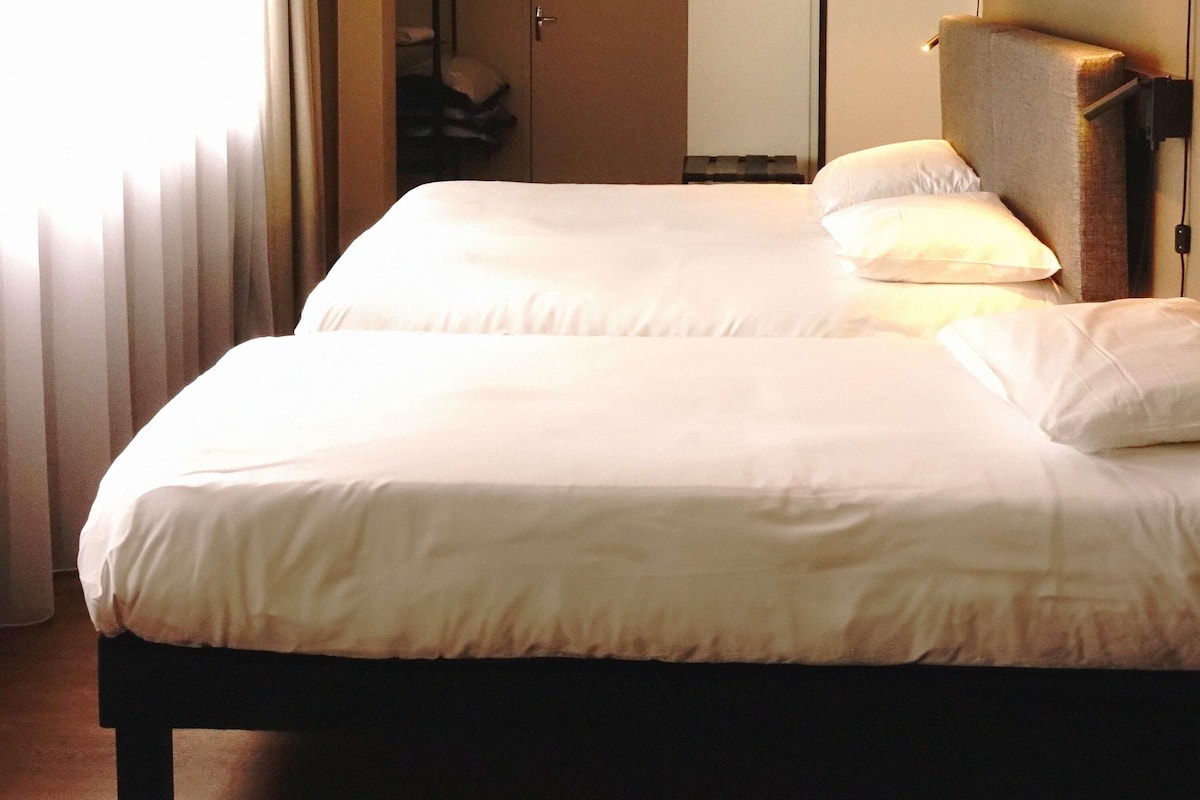 A neatly made bed with white linens, a wooden headboard, and a bedside table.