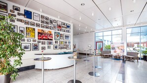 Eine Lobby mit einer Rezeption, gerahmten Bildern an der Wand und Sitzbereichen.