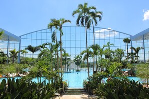 Ein großes Hallenbad mit Palmen und einem Glasgebäude im Hintergrund.