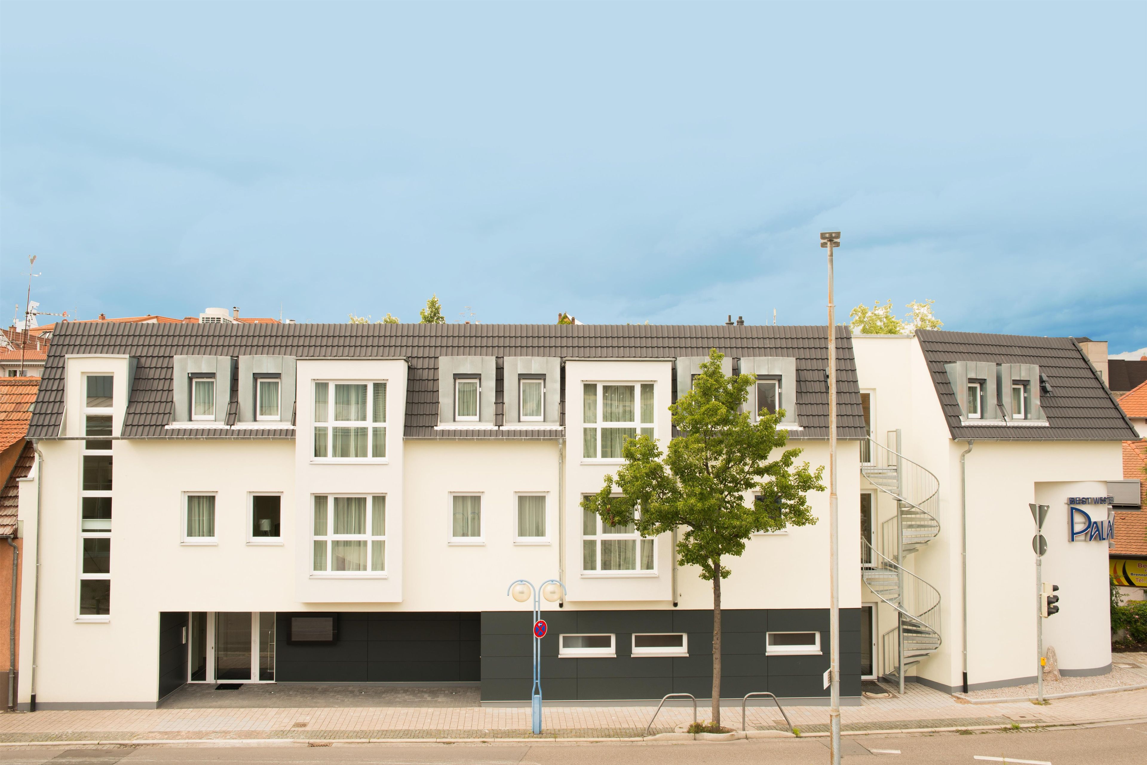 Ein modernes, mehrgeschossiges Wohngebäude mit flachem Dach, zahlreichen Fenstern und einem sichtbaren Garageneingang.