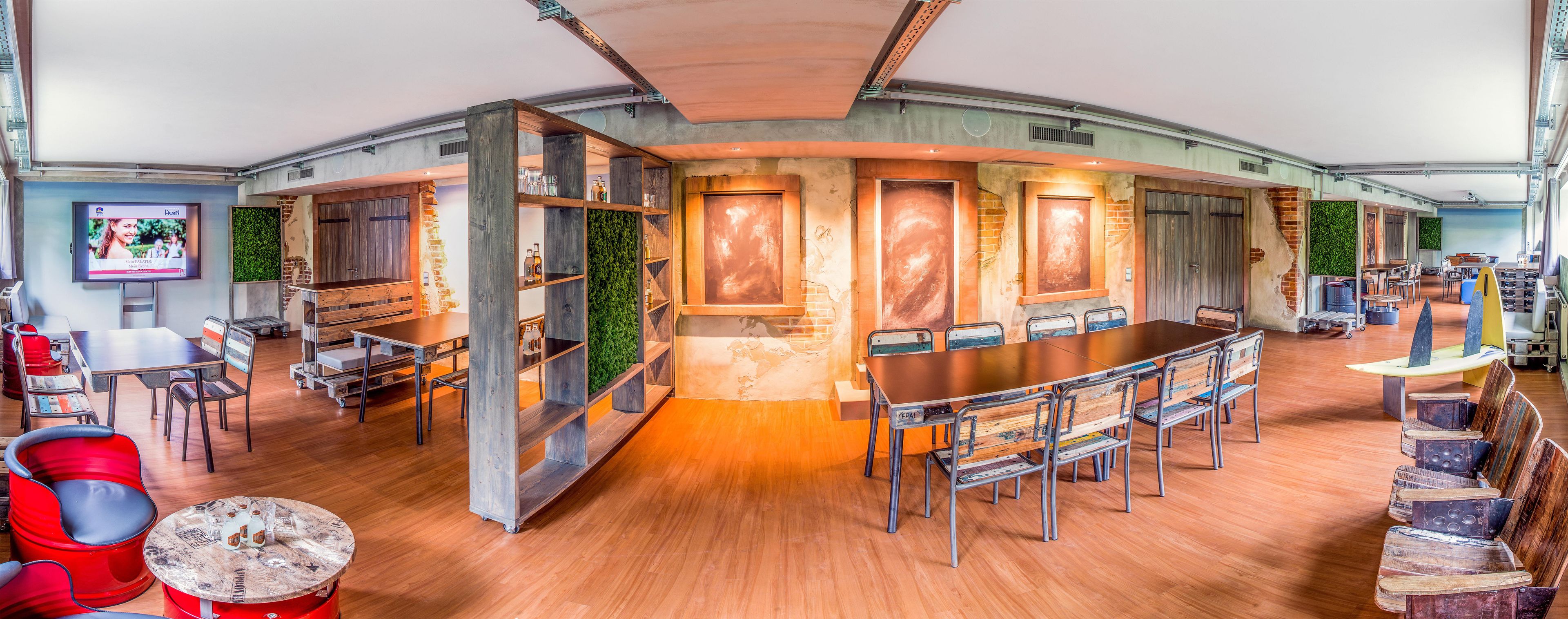 A modern conference room with a long table, chairs, and a television screen.