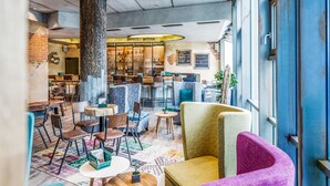 Ein gemütliches Café mit Holztischen und -stühlen, einem großen Baumstamm als Mittelpunkt und einer Bar im Hintergrund.
