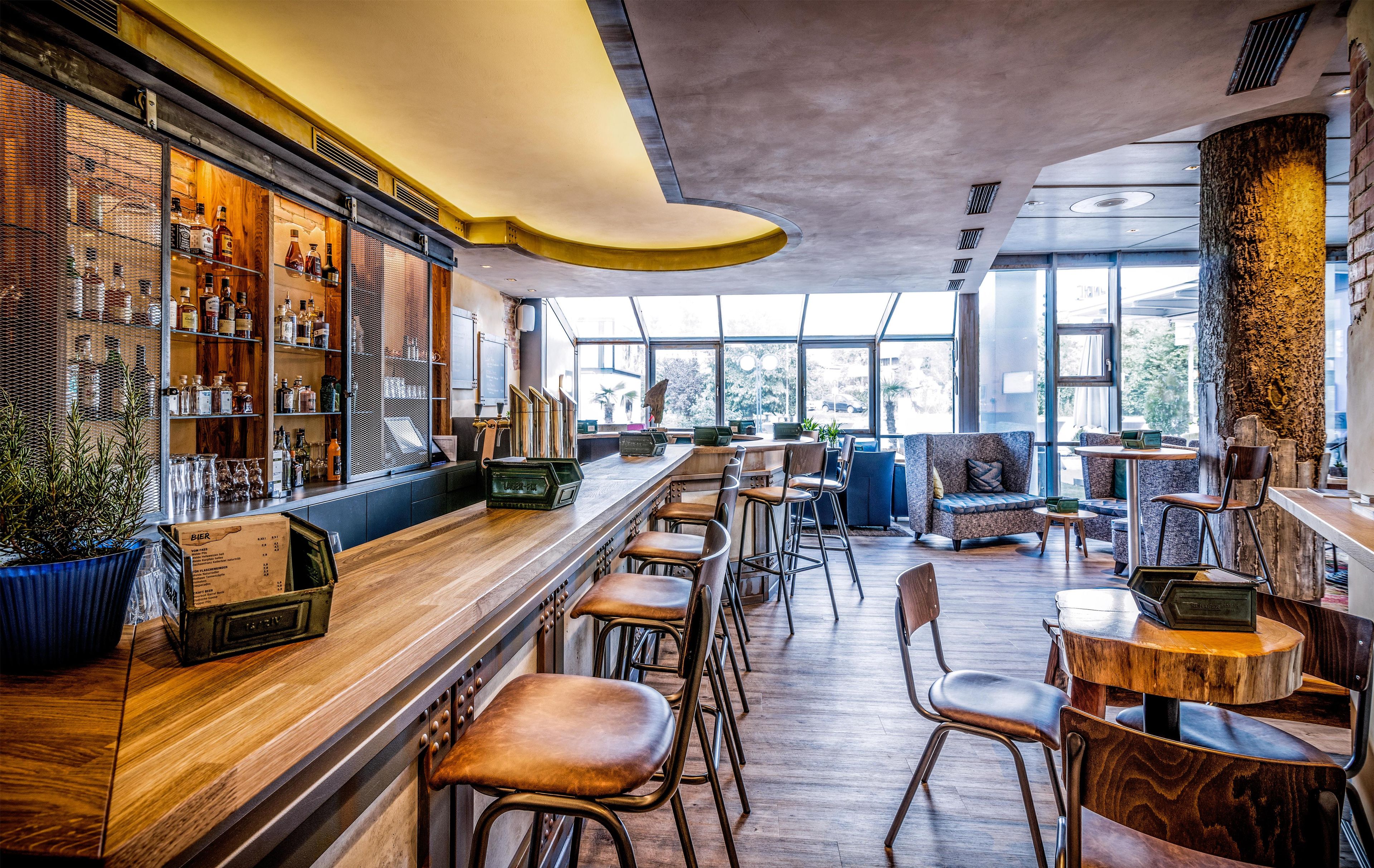 Eine Bar mit Holzböden, Hockstühlen und einer Sitzecke mit Sofas und Tischen.