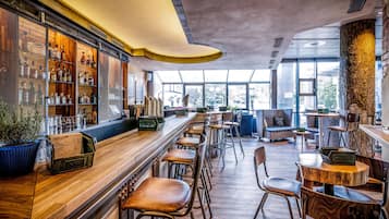 Eine Bar mit Holzböden, Hockstühlen und einer Sitzecke mit Sofas und Tischen.