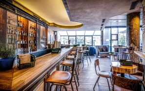 Eine Bar mit Holzböden, Hockstühlen und einer Sitzecke mit Sofas und Tischen.