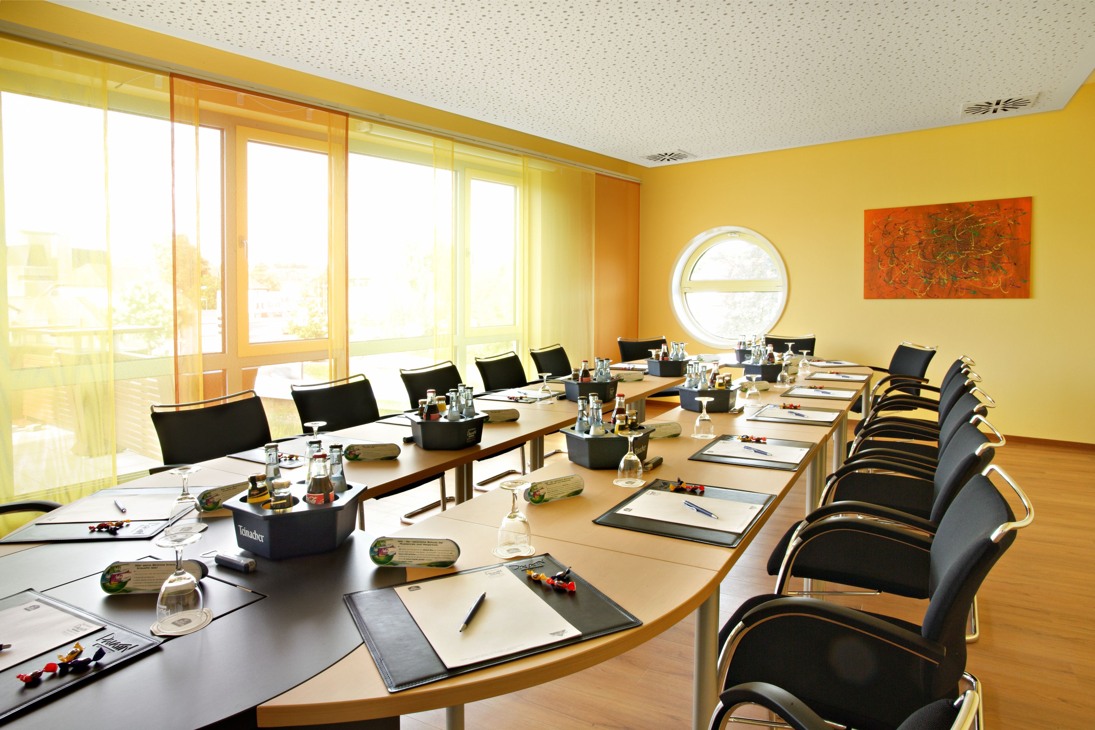 A conference room with a long table, chairs, and various items like glasses and nameplates.