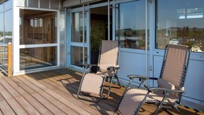 Eine Terrasse mit zwei Liegestühlen und einem Tisch, mit Blick auf eine schöne Aussicht.