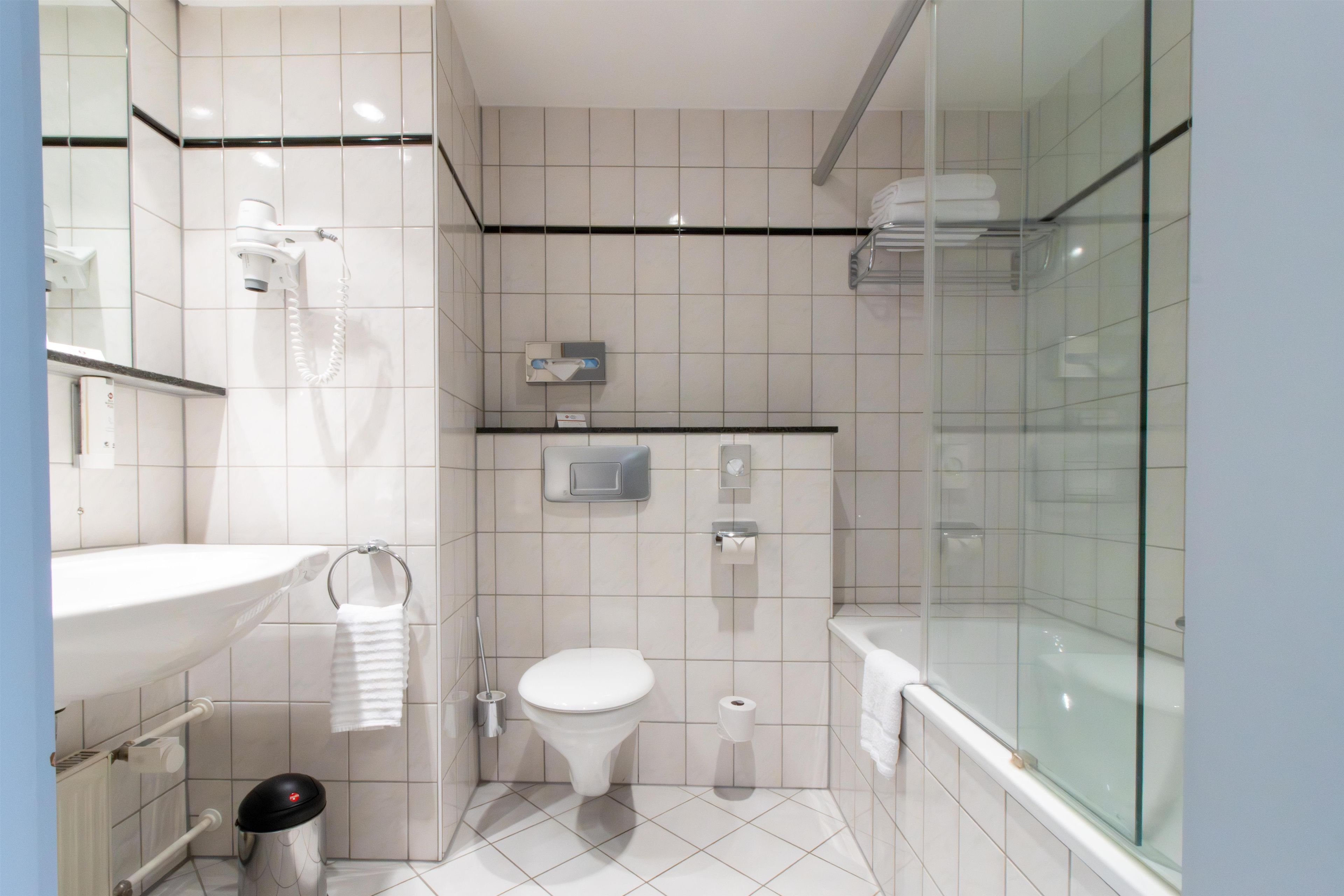 A modern bathroom with a toilet, bidet, and a glass shower enclosure.