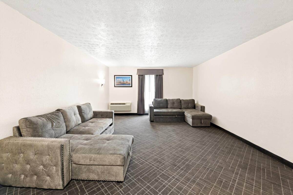 A spacious living room with a sectional sofa, a smaller sofa, and a flat-screen TV.