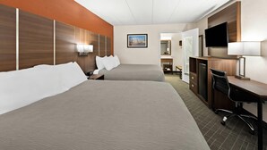 A hotel room with two beds, a desk, a chair, a TV, and a painting on the wall. - Quality Inn Mason Near Kings Island (Mason)