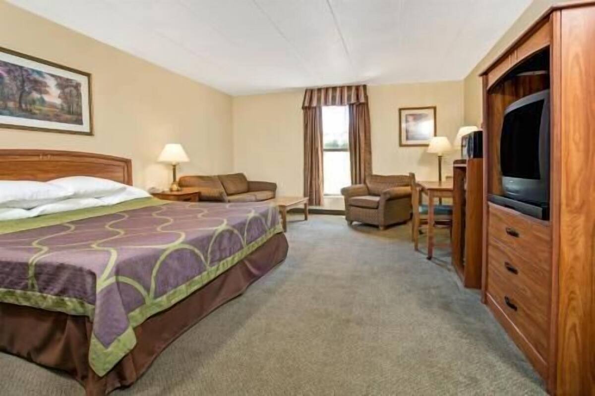 A hotel room with a bed, a television, a desk, and a chair.