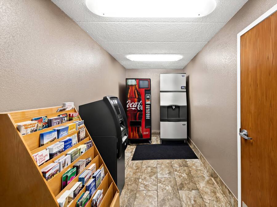 A narrow hallway with a vending machine, a refrigerator, and a bookcase filled with books.