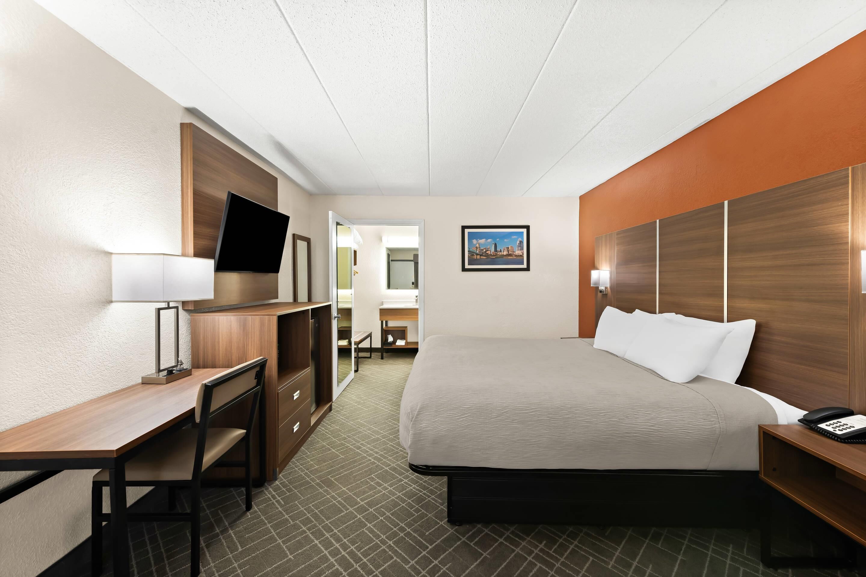 Een hotelkamer met een bed, een bureau, een televisie en een badkamer zichtbaar door een geopende deur.