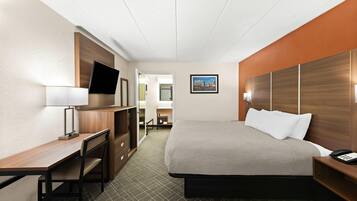Een hotelkamer met een bed, een bureau, een televisie en een badkamer zichtbaar door een geopende deur.
