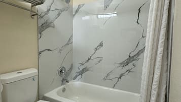 A bathroom with a toilet, bathtub, and shower curtain.