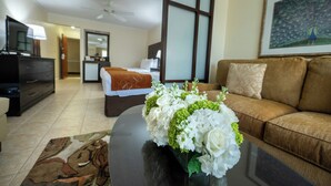 A hotel room with a bed, a sofa, a TV, and a painting on the wall.