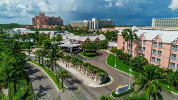 A hotel with a central courtyard, palm trees, and a view of a large resort in the background.