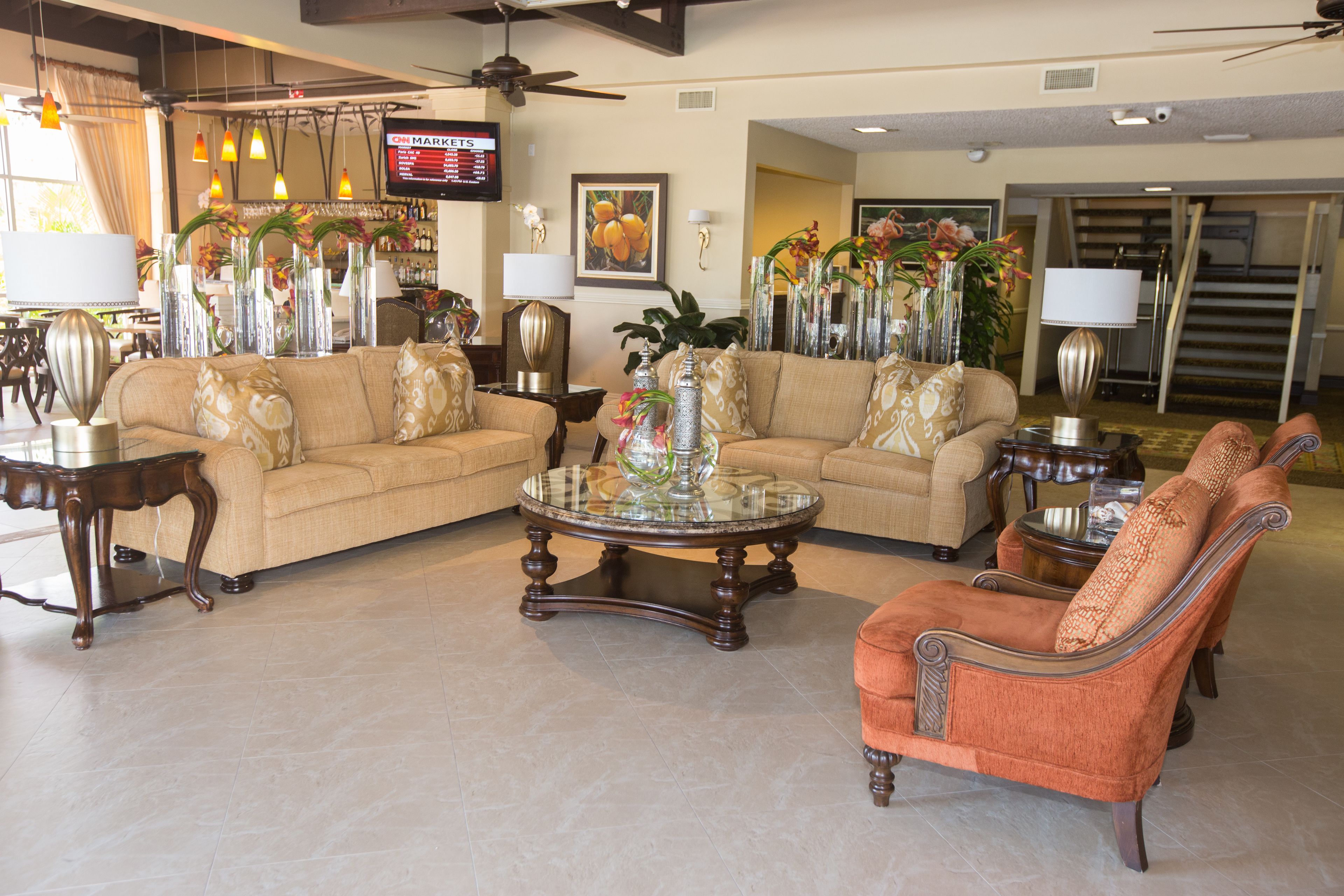 A spacious living room with two sofas, a coffee table, and a fireplace. There is a television mounted on the wall and a staircase leading to the upper floor.