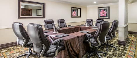 Une salle de conférence avec une longue table, huit chaises et un tapis à motifs.