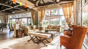 Un vestíbulo amplio con techo alto, ventanas grandes y una variedad de asientos, incluyendo sofás y sillones.