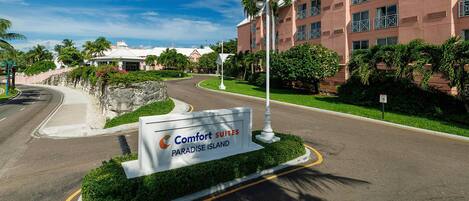 A sign for Comfort Suites Paradise Island with a road curving to the left.