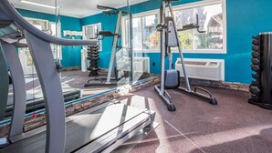 Une salle de sport équipée de matériel d’exercice, dotée d’un grand miroir et d’une fenêtre donnant sur l’extérieur.