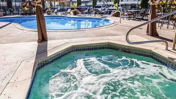 Un bain à remous avec un bord carrelé et une piscine en arrière-plan.