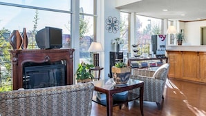 Un salon spacieux avec une cheminée, des canapés à motifs, une table basse et une vue sur l’extérieur.