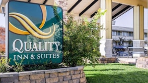 Une enseigne pour le Quality Inn & Suites, avec un mur en pierre et de la verdure à l'avant.