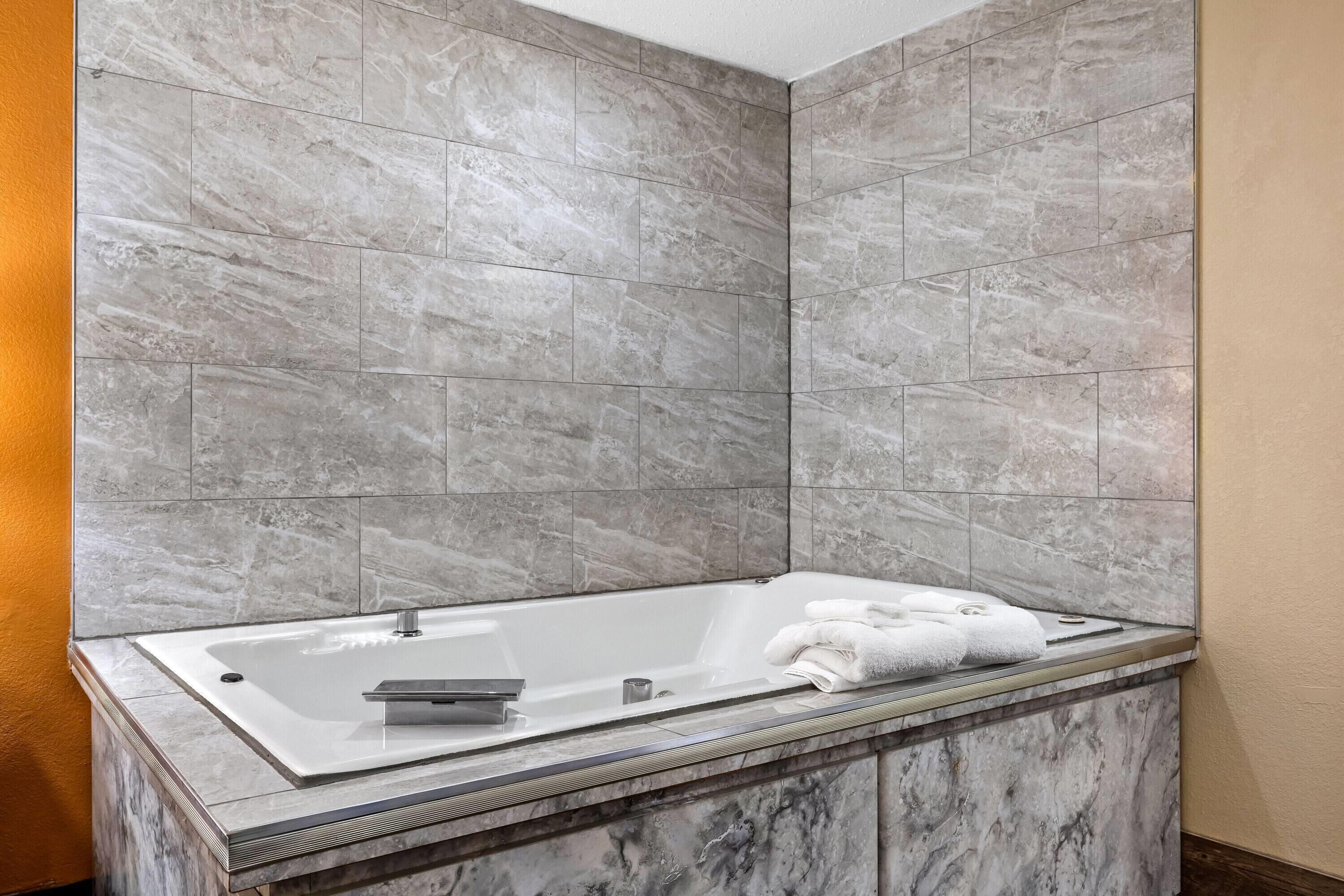 Un baño moderno con una bañera independiente, paredes de mármol y encimera de mármol.