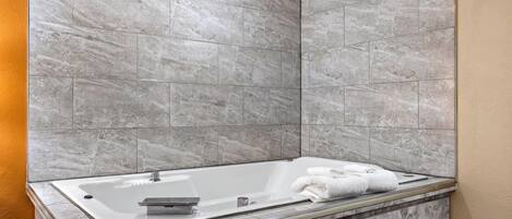 Un baño moderno con una bañera independiente, paredes de mármol y encimera de mármol.