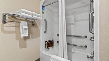 Una ducha con puerta de vidrio, un perchero con toallas dobladas y un cabezal de ducha de mano.