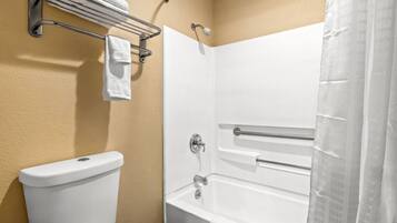 A bathroom with a white toilet, a bathtub with a shower curtain, and a towel rack with towels.