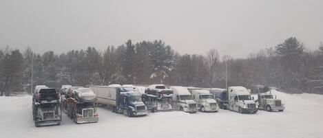 Un estacionamiento cubierto de nieve con varios camiones y remolques.