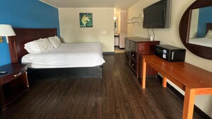 A hotel room with a bed, a TV, a dresser, and a desk. - Capitol Inn by Belvilla Richmond Airport VA (Sandston)