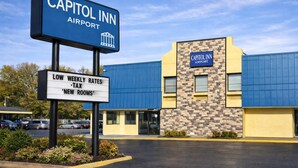 A Capitol Inn Airport sign and building with a clear view of the entrance and parking area. - Capitol Inn by Belvilla Richmond Airport VA (Sandston)