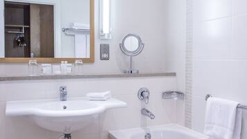 A modern bathroom with a sink, mirror, and bathtub.