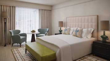 Una habitación de hotel con cama, dos sillas, una mesita, un banco y una mesita de noche con lámparas.