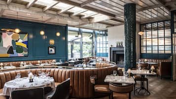 En restaurang med en böjd sittgrupp, synliga träbjälkar i taket och stora fönster.