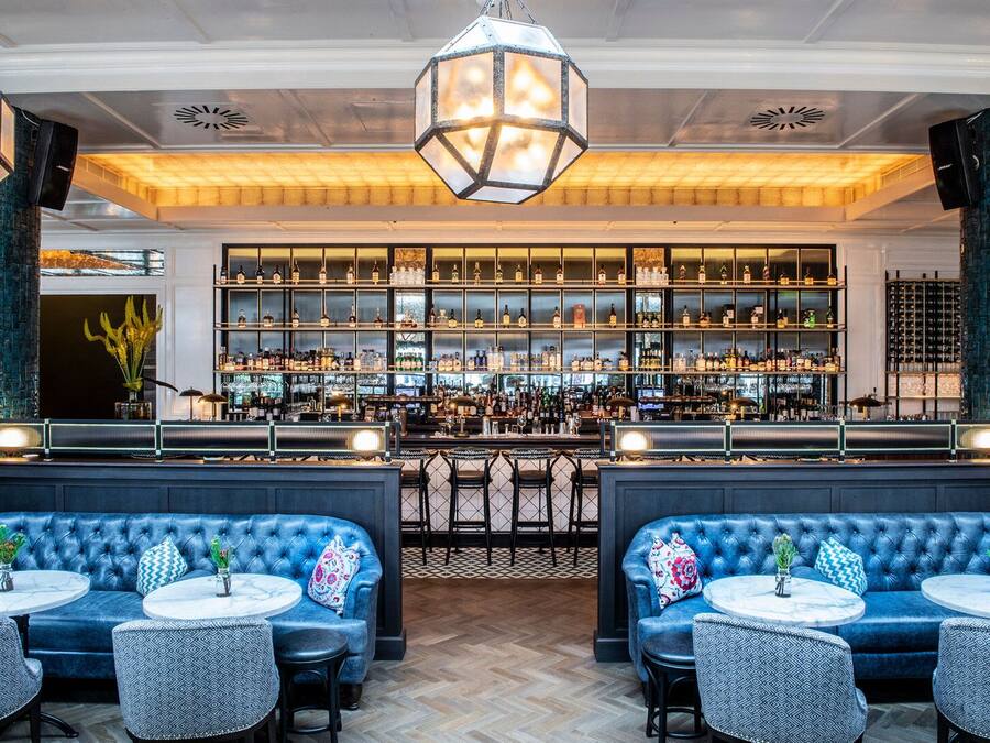 A bar area with blue upholstered seating, a well-stocked liquor display, and a patterned floor.