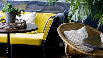 A cozy seating area with a yellow sofa, wicker chairs, and a small table with a plant.