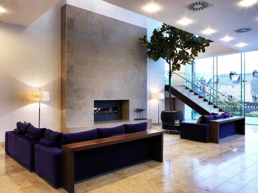 Un vestíbulo amplio con chimenea, zona de estar y una escalera que conduce a los pisos superiores.