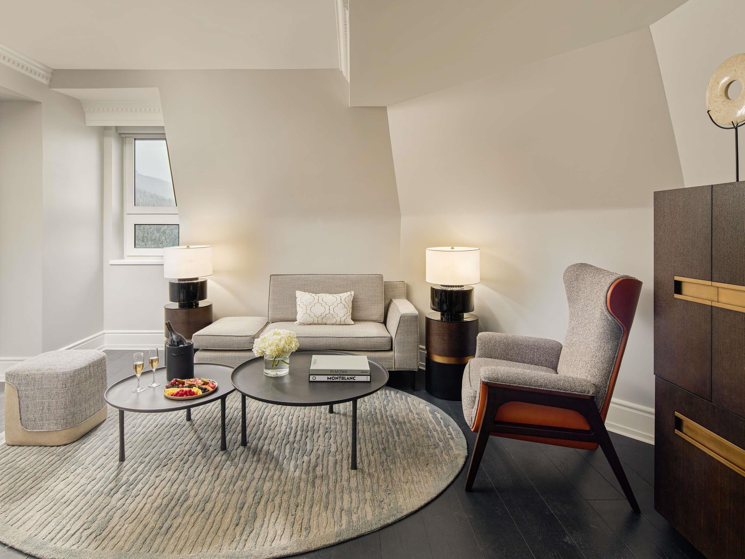 A modern living room with a sofa, two armchairs, a coffee table, and a sideboard.
