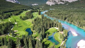 A golf course with a river, surrounded by forest and mountains. - Fairmont Banff Springs (Banff)