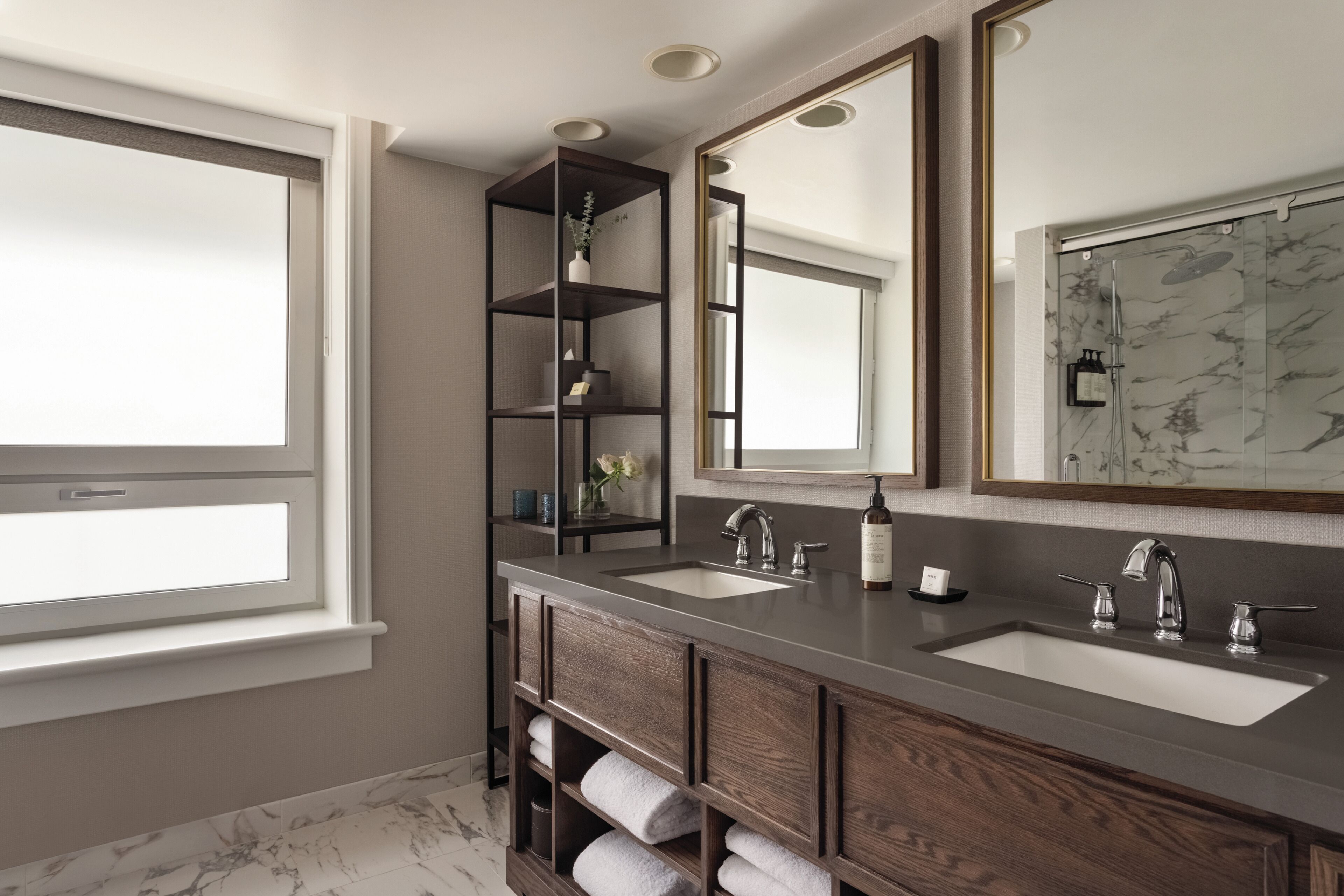 Un baño moderno con dos lavamanos, un espejo grande y estantes empotrados.